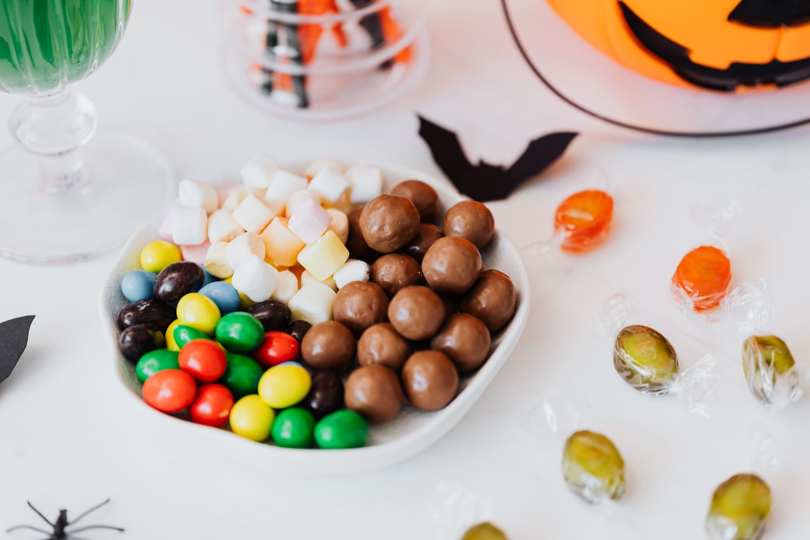 Bowl of Halloween candy and chocolate next to a jack-o-lantern decoration