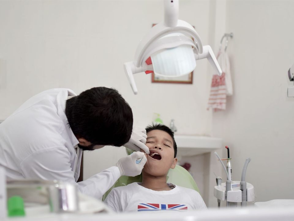 Pediatric dentist examining a young boy's teeth during a checkup at our Christiansburg, VA dental office